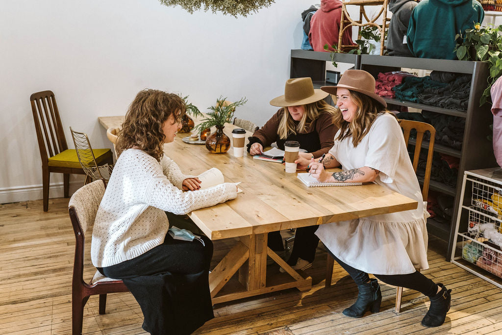 People sit around a wooden table with notepads